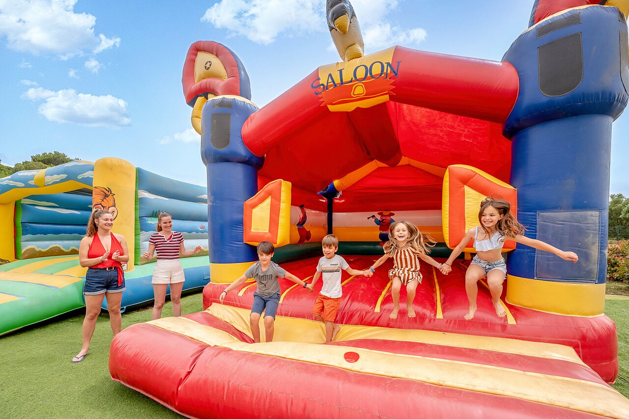 Children jumping on giant inflatable Saloon structure at CAPFUN Vignes d'Or campsite Serignan.