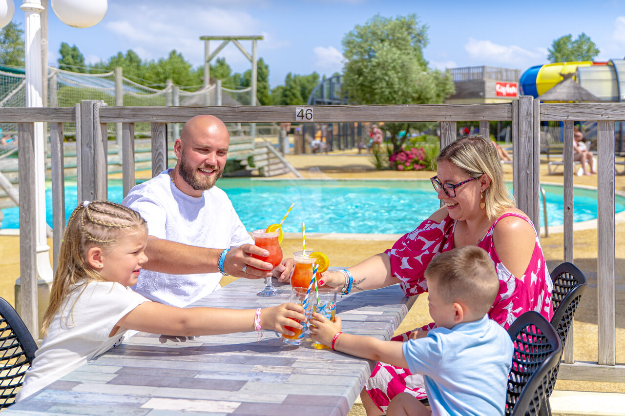 Family with drinks by the pool at CAPFUN Vikings campsite in Saint Jean de la Rivi�re (50).