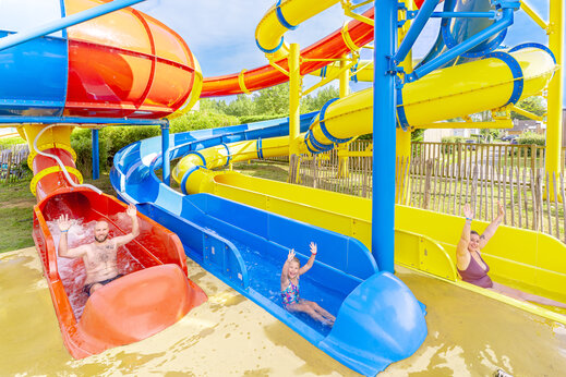 Colorful giant water slides with campers at CAPFUN Vikings campsite.