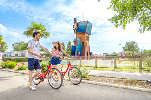 Couple cycling, giant children's play tower at CAPFUN Vikings campsite (50).