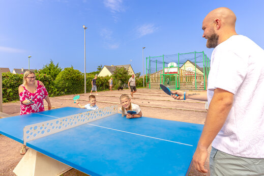 Family playing table tennis on blue table at CAPFUN Vikings campsite in Saint Jean de la Rivi�re (50).