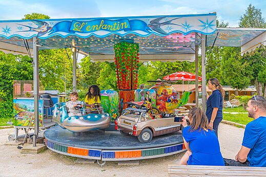 Children's carousel with cars and helicopter at CAPFUN Le Village Parisien campsite.