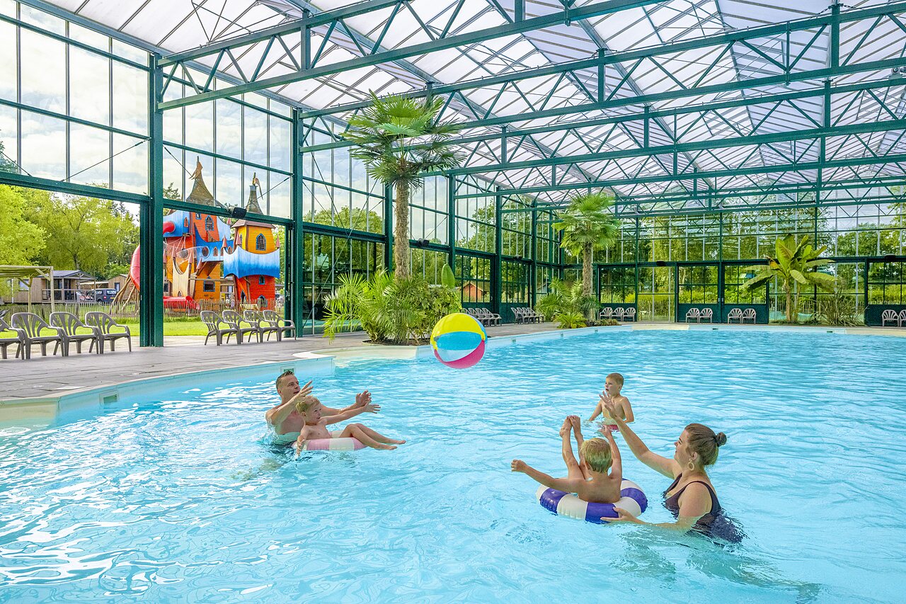 Indoor swimming pool, family playing, at CAPFUN Vlinderloo campsite in Enschede.