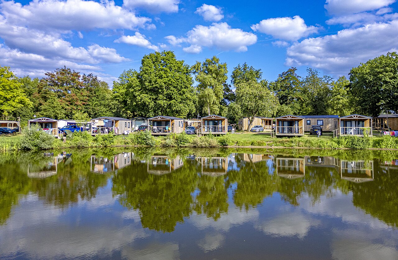 Wooden mobile homes by the lake, green nature, at CAPFUN Vlinderloo campsite in Enschede.