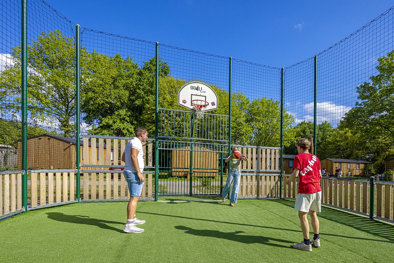 Multisport court with basketball and players at CAPFUN Vlinderloo campsite in Enschede.