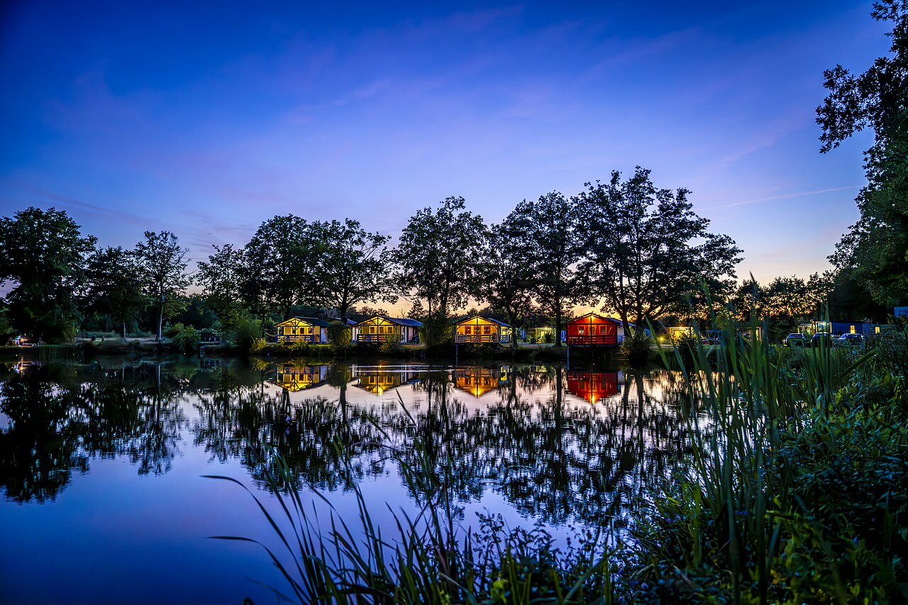 Illuminated Mobil-homes by the lake at CAPFUN Vlinderloo campsite in Enschede.
