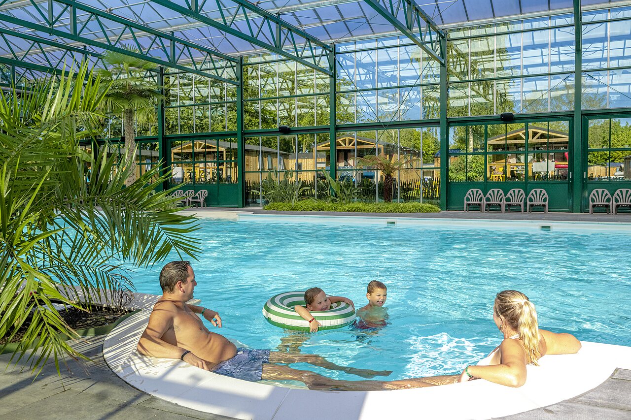 Family enjoying the covered swimming pool with Mobile Homes at CAPFUN Vlinderloo campsite in Enschede.