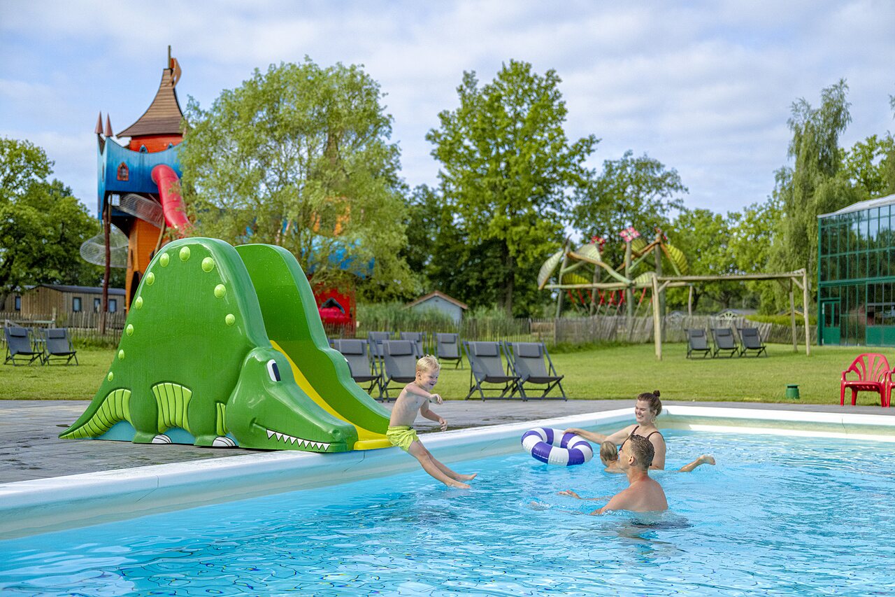 Outdoor swimming pool with crocodile slide and children at CAPFUN Vlinderloo campsite in Enschede.