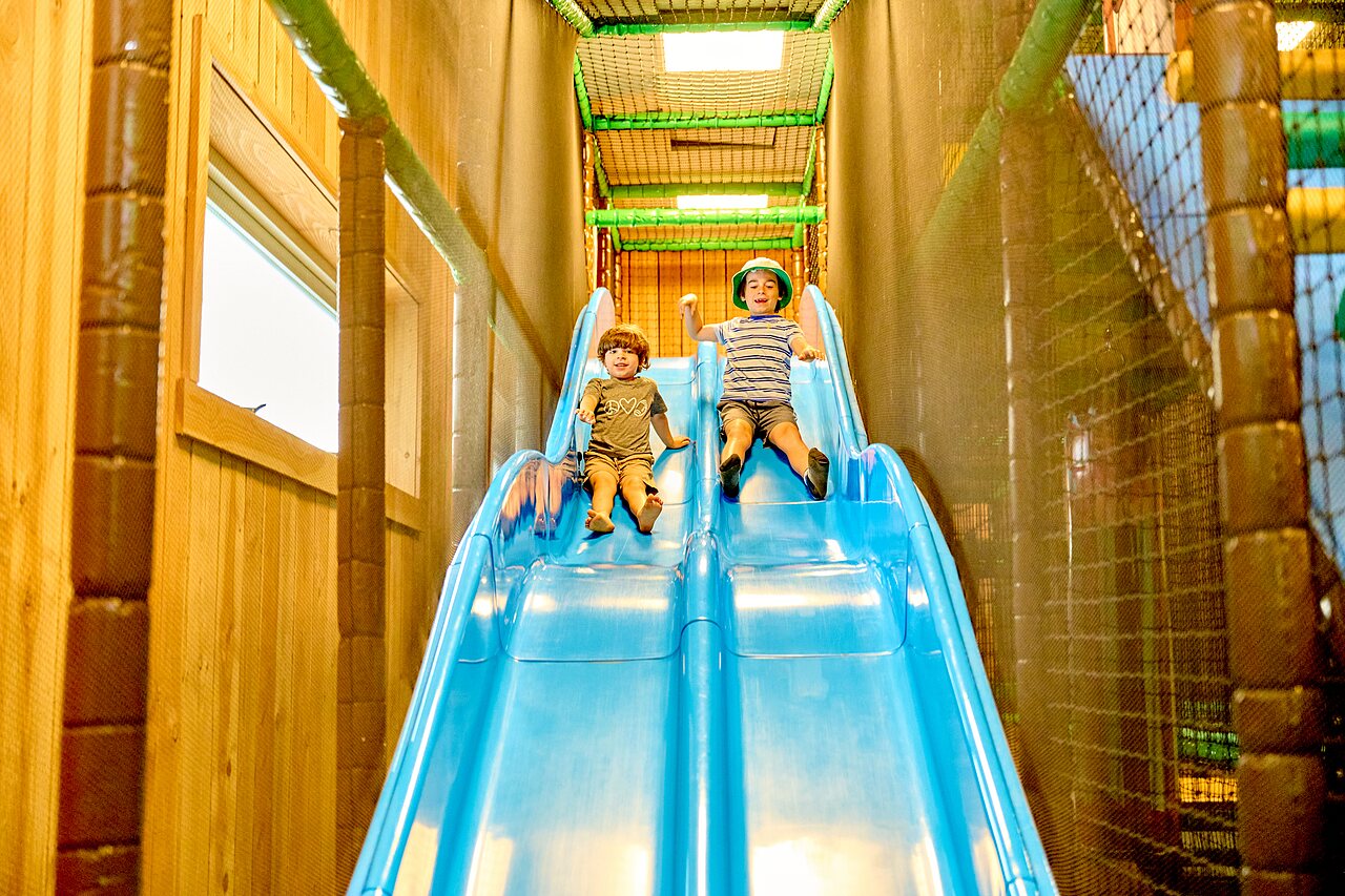 Children on blue slide indoor play area at CAPFUN De Waldsang campsite Bakkeveen.