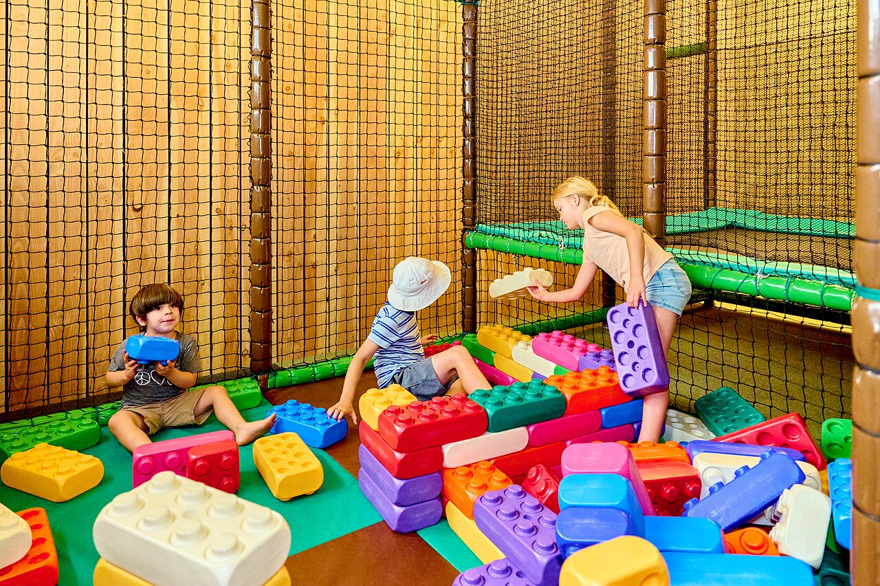 Children playing with giant blocks in the indoor play area at CAPFUN De Waldsang campsite in Bakkeveen.