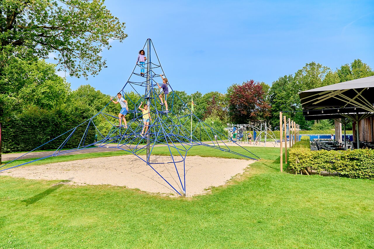 Children climbing rope play structure at CAPFUN De Waldsang campsite in Bakkeveen.