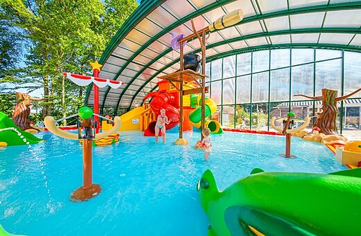Covered water park with slides and water games at CAPFUN De Waldsang campsite.
