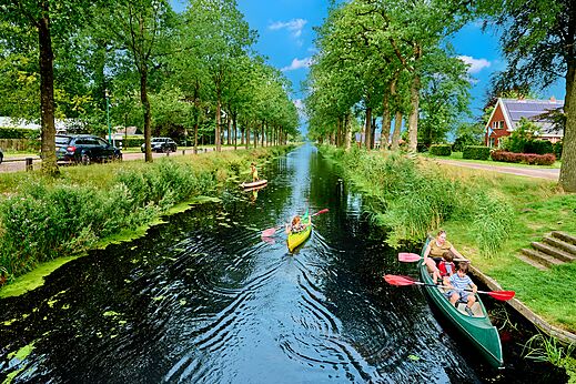Water activities on the tree-lined canal at CAPFUN De Waldsang campsite in Bakkeveen.