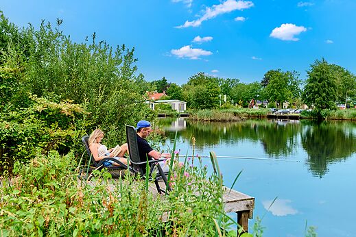 Couple fishing and relaxing by the water at CAPFUN De Waldsang campsite in Bakkeveen.