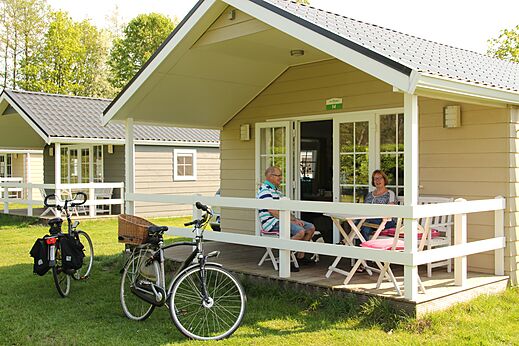 Mobile home with couple on terrace, bikes, at CAPFUN het Winkel Winterswijk.