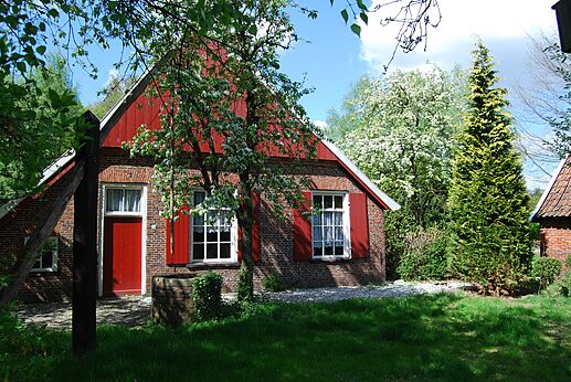 Traditional brick house, red shutters, flowery garden at CAPFUN het Winkel campsite in Winterswijk.