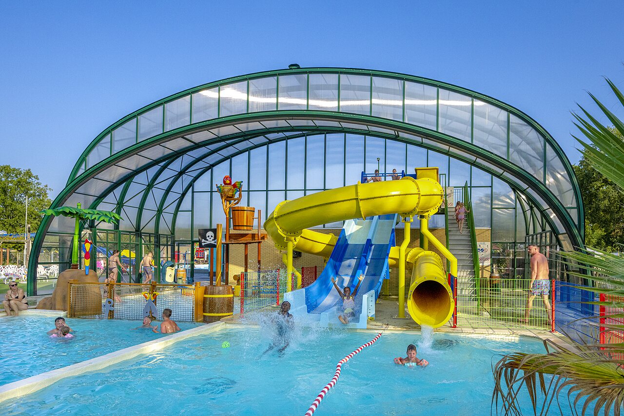 Covered swimming pool with water slides and children's games at CAPFUN Wondermolen campsite in Molenschot.