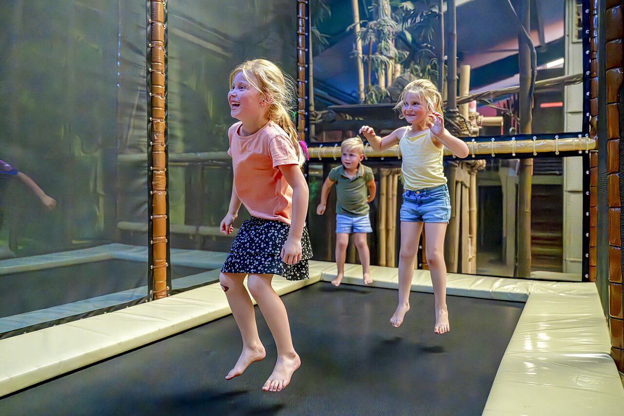 Smiling children jumping on indoor trampolines at CAPFUN de Wondermolen campsite in Molenschot.