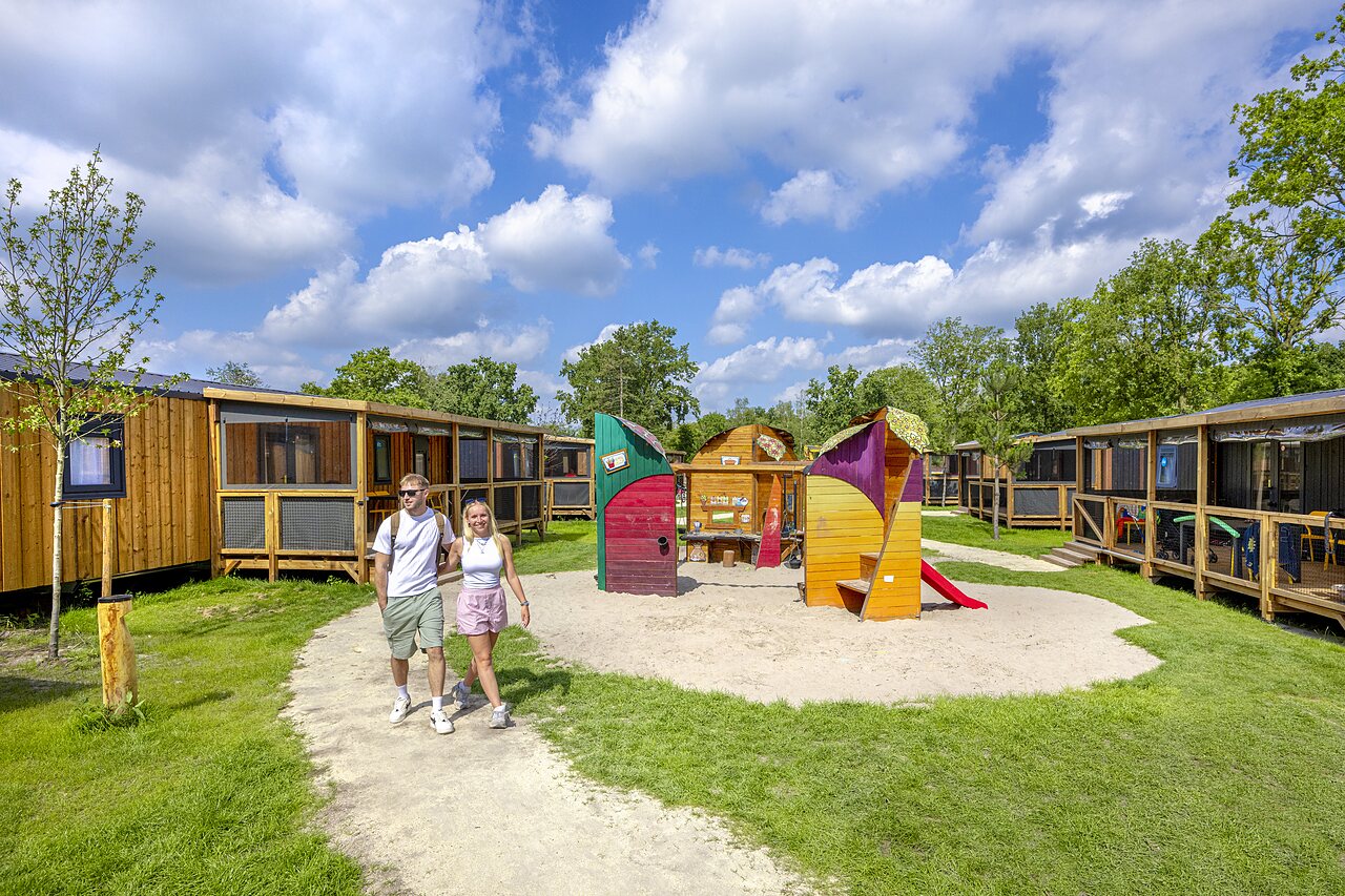 Wooden mobile homes and colorful playground at CAPFUN de Wondermolen campsite in Molenschot.