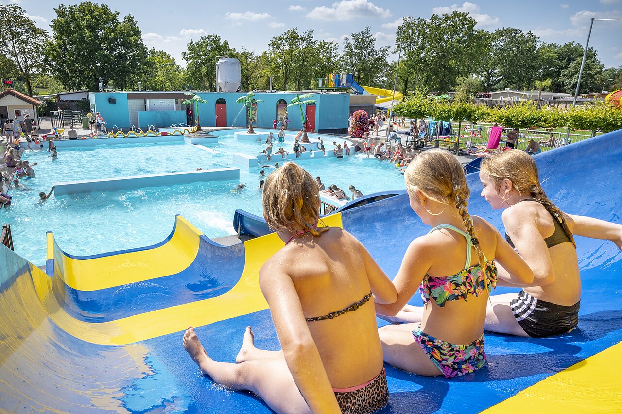 Children on water slide, lively outdoor swimming pool at CAPFUN de Wondermolen campsite in Molenschot.