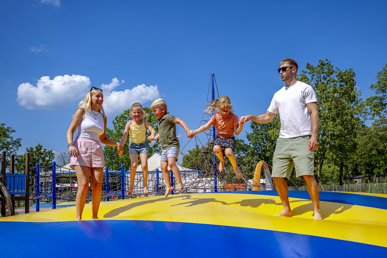 Family jumping on giant inflatable pillow at CAPFUN Wondermolen campsite in Molenschot.