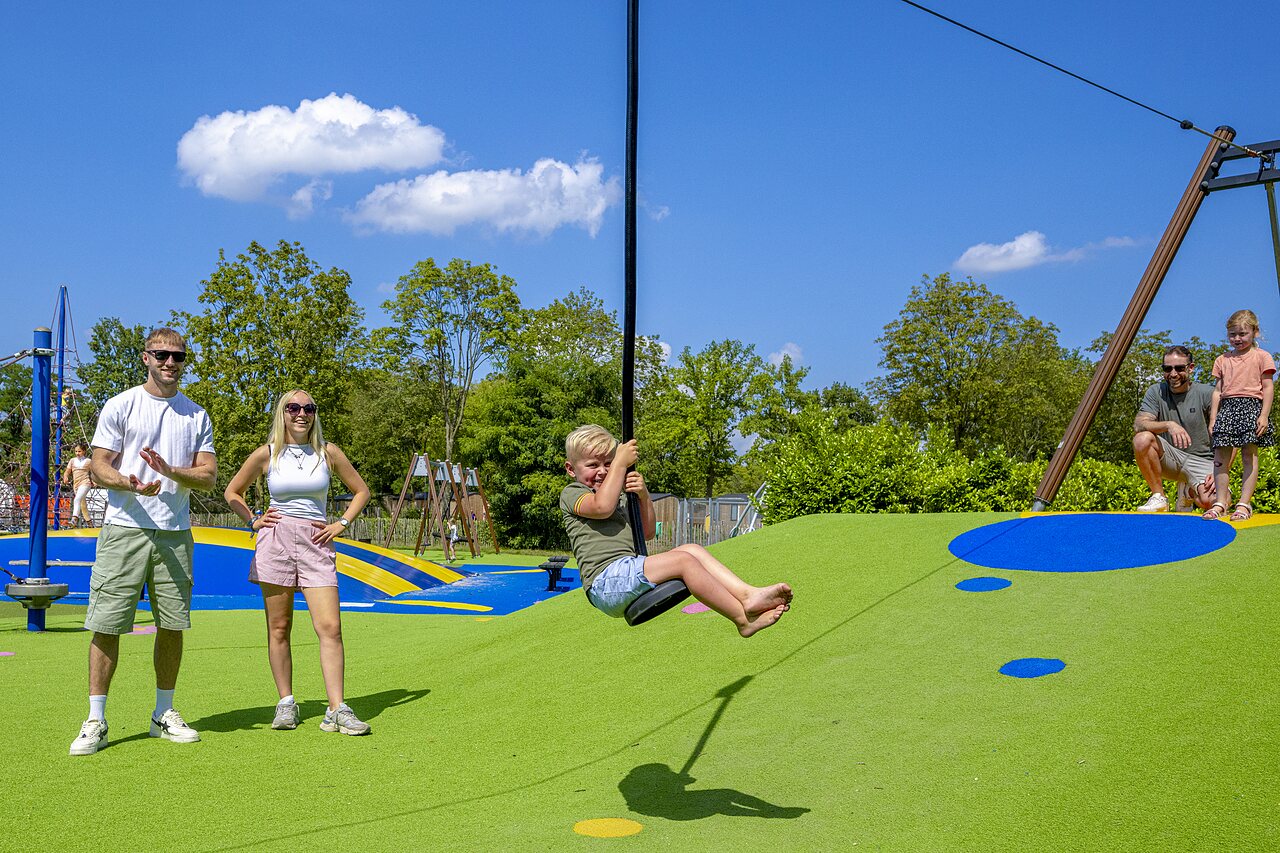 Smiling child on modern zip line in the playground at CAPFUN de Wondermolen campsite in Molenschot.