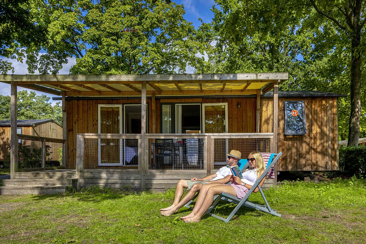 Couple relaxing in front of mobile home at CAPFUN Wondermolen campsite in Molenschot.