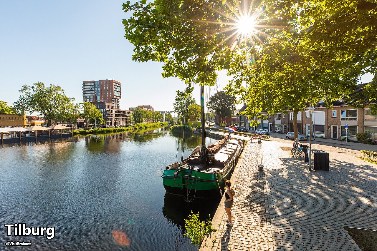 Urban canal with boat and modern buildings in Tilburg, North Brabant.