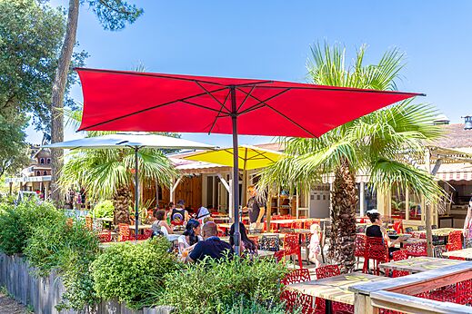 Outdoor restaurant terrace with colorful parasols and guests at CAPFUN Zagarella campsite in LONGEVILLE SUR MER (85).