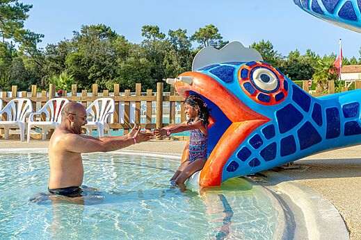 Child sliding down fish water slide into pool at CAPFUN Zagarella, LONGEVILLE SUR MER (85).