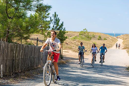 Family cycling on coastal path at CAPFUN Zagarella campsite in LONGEVILLE SUR MER.
